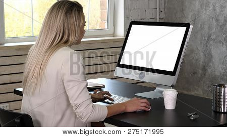 Business Woman In Dress Sitting On Workplace Near The Window And Using Computer In Office. White Dis