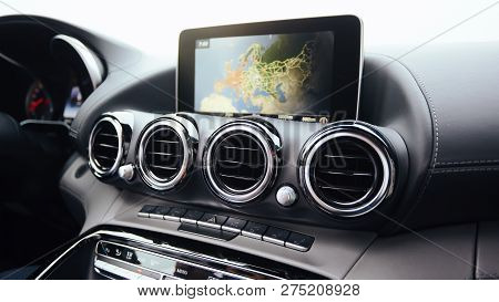 View From Inside A Car On A Part Of Dashboard With A Navigation Unit And Blurred Street In Front Of 