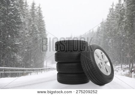 Set Of Winter Tires On Forest Highway During Snowfall. Car Service