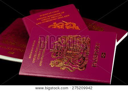 A Stack Of Old And New Uk Passports Isolated On A Black Background