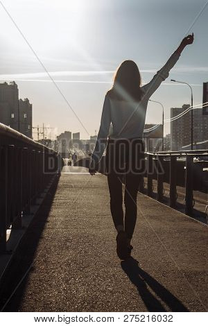 The Girl Goes On The Road Towards Sunset And Waving