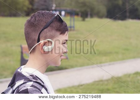Close Up Side Portrait Of Stylish Boy With Earphones Posing Outdoors. Happy Child With Trendy Sungla