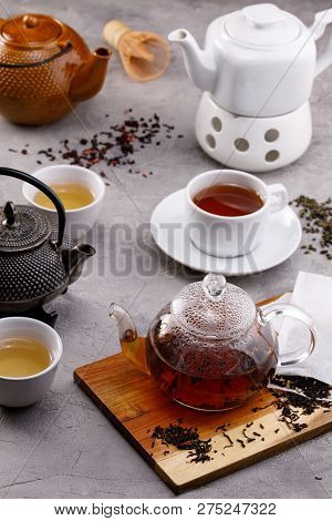 Tea Card. Different In Appearance Teapots On A Gray Background, Different Types Of Tea. Tea Still Li