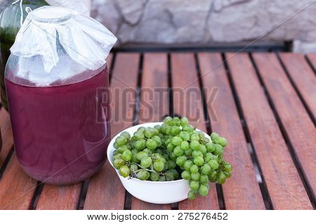 Bunches Of Yellow-green Ripe Grapes From An Organic Garden. Big Wine Bottles Aback. Settled On The W