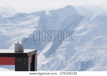 Old Table With Sugar Bowl In Outdoor Cafe At Ski Resort And Snowy Sunlight Mountains At Background. 