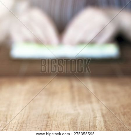 Making Sushi Rolls Concept: Wooden Board And Blurred Woman Hands Placing The Filling In The Middle O