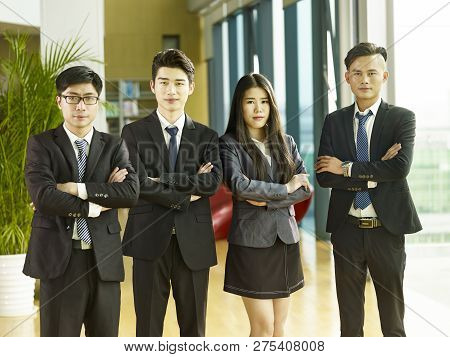 Portrait Of A Group Of Young Asian Business People Standing In Office Arms Crossed, Looking At Camer
