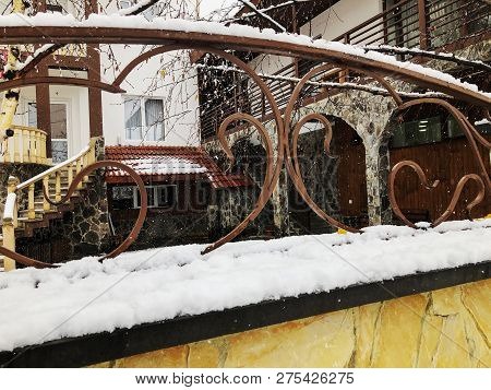 Srone Gate With Decorative Steel Trim. Snowfall On The Street.noon.