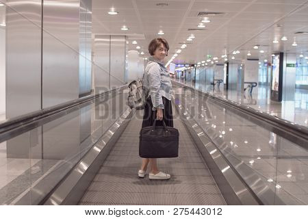 The Girl Is Riding On The Travolator At The Airport With A Laptop. Toned