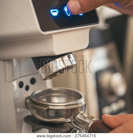Extracting The Flavor From The Beans. Coffee Grinder Grinding Roasted Beans In Powder. Barista Grind
