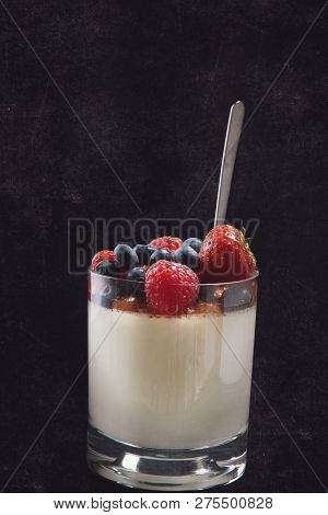 Panakota Creamy Italian Dessert In A Glass Beaker With Berries On A Dark Background