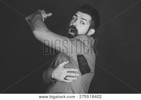 Man With Beard Wears Jacket With Hole On Dark Background. Bad Quality Of Clothes Concept. Surprised 