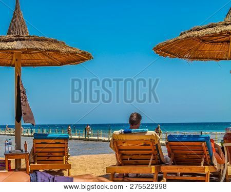 View Of The Beach And Vacationers In Loungers On The Shores Of The Red Sea Sunburn In The Sun On Vac