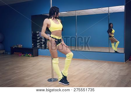 Young Sexy Striptease Dancer Training In Dance Studio. Dancer Posing Near Pole And Looking At The Mi