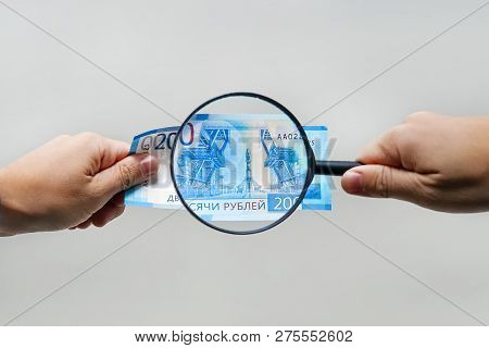 Russian Currency, Including New 2000 Rouble Bills. Mens Hands Hold 2000 Rubles And A Magnifying Glas
