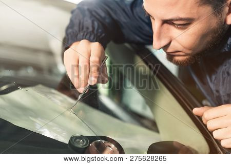 Close Up Automobile Glazier Worker Fixing And Repair Windscreen Or Windshield Of A Car In Auto Servi