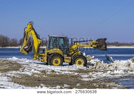 Excavator Works On The Rivershore. Cleaning Shore Of Ice And Snow.