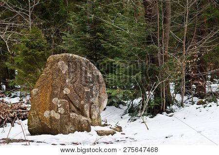 Ancient Large Stones With Engraving At Green Forest With Little Snow Cover In Carpathians Mountains.