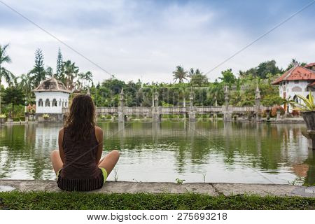 Girl Sitting On Pier And Lookingat The River In Bali