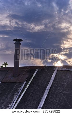 Old Roof Of A Russian Bath Against The Evening Cloudy Sky