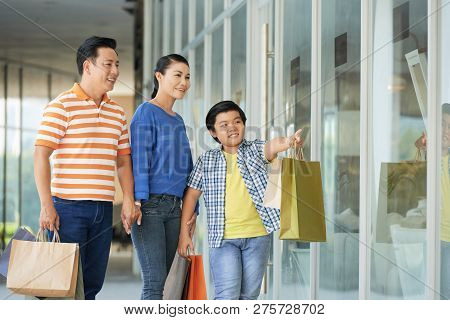 Vietnamse Teenage Boy Showing His Parents Something Interesting In Shop Window