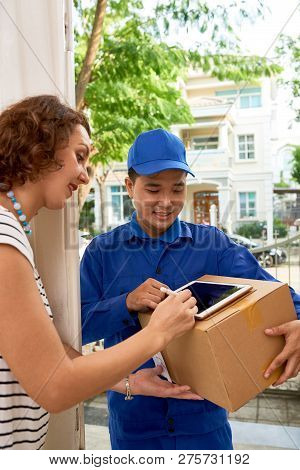 Woman Siging Document On Digital Tablet When Receiving Package