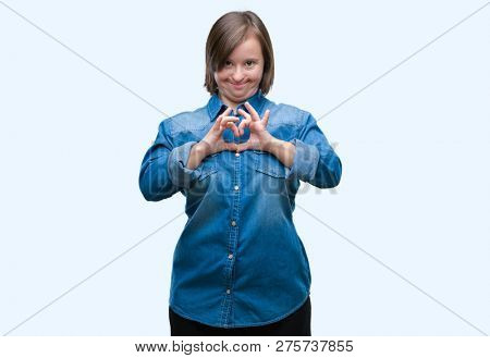 Young adult woman with down syndrome over isolated background smiling in love showing heart symbol and shape with hands. Romantic concept.