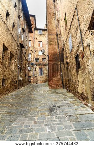 Medieval Narrow Street Vicolo Del Tone In Old City Siena, Tuscany, Italy.