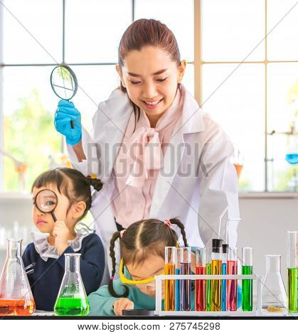 Science Teacher Teach Asian Students In Laboratory Room, Teacher Use Magnifying Glass To Look Throug