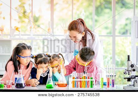 Science Teacher Teach Asian Students In Laboratory Room, Boy Drop Something Into Orange Tube, Colorf