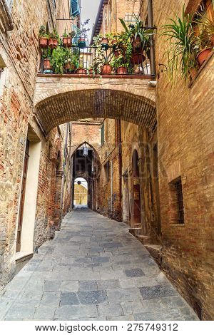 Medieval Narrow Street Vicolo Delle Scotte In Old City Siena. Tuscany, Italy.