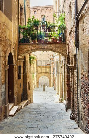 Medieval Narrow Street Vicolo Delle Scotte In Old City Siena. Tuscany, Italy.