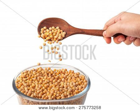 Spoon In Hand With Yellow Peas On White Background. Peas In Glass Bowl