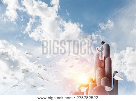 Young Female Doctor With Folder In Hands Satnding On Stone Column
