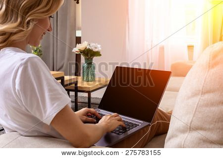 Woman On Sofa Working On Laptop With Mockup Blank Screen. Empty Copy Space On Monitor For Advertisem