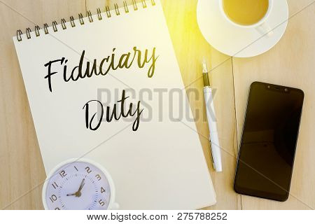 Top View Of Clock,mobile Phone,pen, A Cup Of Coffee And Notebook Written With Fiduciary Duty On Wood