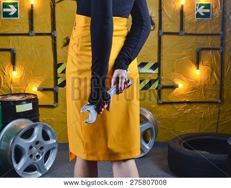 Stylish Mechanic Girl In Trendy Clothes Is Holding A Wrench On The Background Of The Workshop Of An 