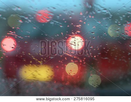 Abstract Pattern Of Colorful Lights And Rain Drops During Downpour On Winshield Of Car After Dark