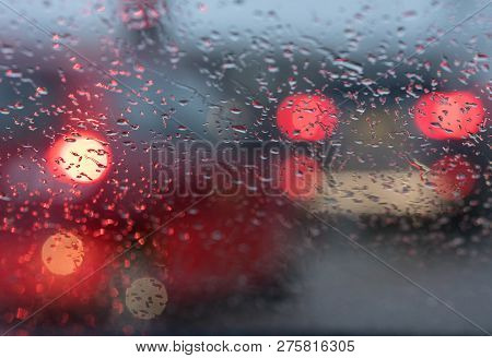 Abstract Pattern Of Colorful Lights And Rain Drops During Downpour On Winshield Of Car After Dark