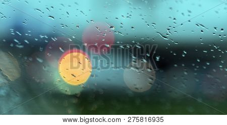 Abstract Pattern Of Colorful Lights And Rain Drops During Downpour On Winshield Of Car After Dark