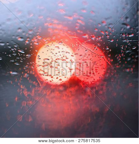 Abstract Pattern Of Colorful Lights And Rain Drops During Downpour On Winshield Of Car After Dark