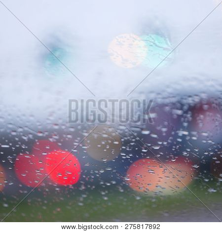 Abstract Pattern Of Colorful Lights And Rain Drops During Downpour On Winshield Of Car After Dark