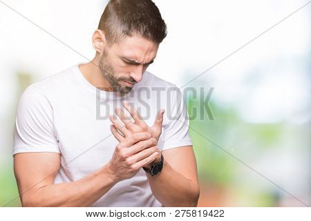 Handsome man wearing white t-shirt over outdoors background Suffering pain on hands and fingers, arthritis inflammation