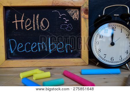 Hello December. Back To School Concept. Alarm Clock On Wooden With Blackboard On Background