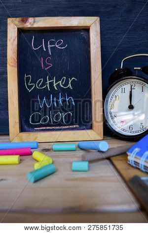 Life Is Better With Color. Back To School Concept. Alarm Clock On Wooden With Blackboard On Backgrou