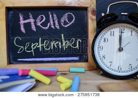 Hello September. Back To School Concept. Alarm Clock On Wooden With Blackboard On Background
