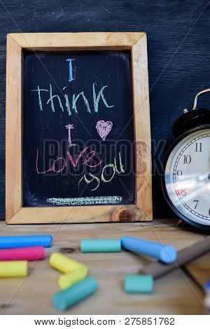 I Think I Love You. Back To School Concept. Alarm Clock On Wooden With Blackboard On Background