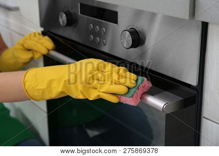 Woman Cleaning Kitchen Oven With Sponge, Closeup