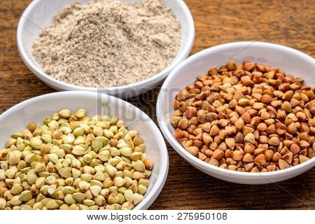 gluten free buckwheat groats, roasted kasha and flour - a set of small ceramic bowls against rustic wood