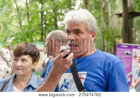 Komsomolsk-on-amur, Russia - August 19, 2018. Elderly Man Prepares To Inhale Before Blowing Into The